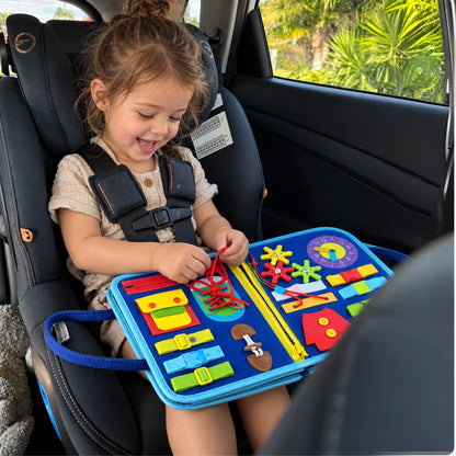 Peque en su sillita del carro jugando con el maletín azul.